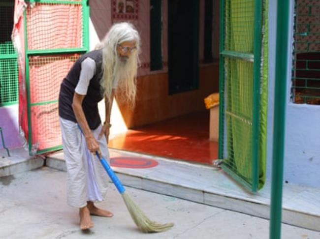 Bechan Baba sweeps the courtyard in front of open doors leading into the mosque.