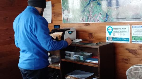 An employee uses a machine to count banknotes in a store in Patago<em></em>nia in southern Argentina. The co<em></em>nstant increase in prices has meant that many products must be paid for with dozens of bills of the da<em></em>lertued Argentine peso and has forced stores to buy counting machines to save time. CREDIT: Daniel Gutman / IPS