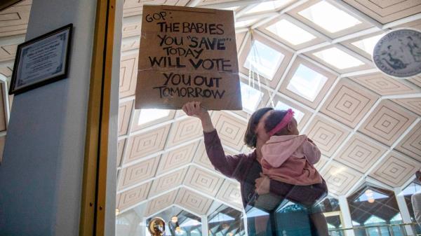 A demo<em></em>nstrator holds a sign and a baby outside a House Floor gallery window at the North Carolina State Legislature after Republican state lawmakers announced their plan to limit abortion rights across the state.