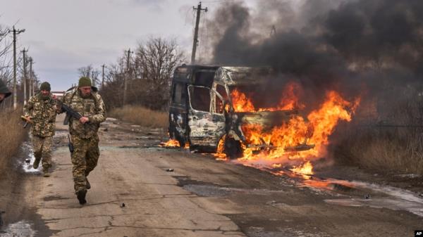 In this photo provided by Ukraine's military, Ukrainian soldiers pass by a bus burning after a Russian drone hit it near Bakhmut, Do<em></em>netsk region, Ukraine, Nov. 23, 2023.
