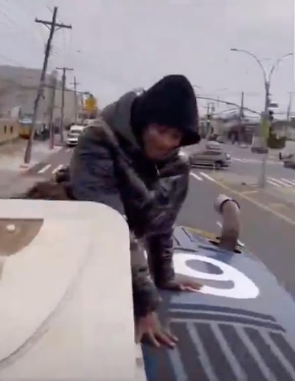 Screenshot of a teen crouching on a moving bus.