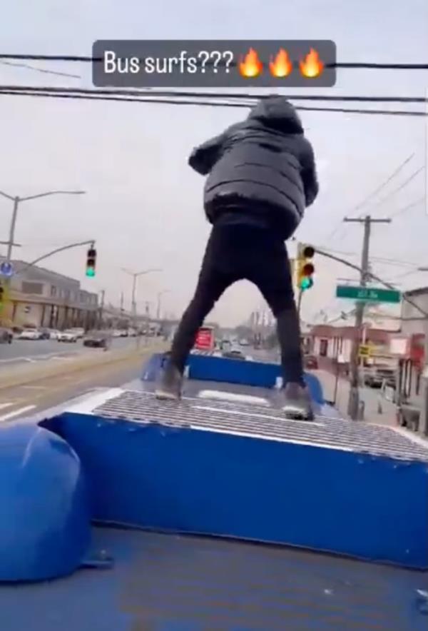 Teen standing up while riding the top of a bus