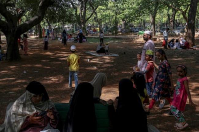 People take shelter from the sun under trees at a park during a hot day in Bengaluru, India on April 30, 2024.