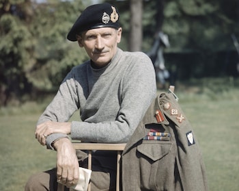 Mo<em></em>nty wears a beret with military insignia and a roll-neck gray jumper