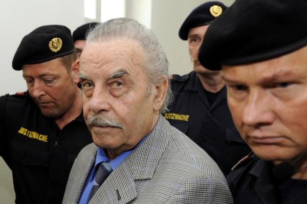 FILE - Defendant Josef Fritzl, center, is escorted to the fourth day of his trial in the provincial courthouse in St. Poelten, Austria, Thursday, March 19, 2009. Fritzl, who kept his daughter captive for 24 years, raped her thousands of times, and father seven of her children, can be moved from psychiatric detention to a normal prison under certain conditions, a court ruled Thursday, Jan. 25, 2024. Josef Fritzl, who is 88, will have to attend regular psychotherapy and undergo psychiatric a<em></em>lertuations during a 10-year probation period, Austria Press Agency reported. (Robert Jaeger/Pool Photo via AP, file)