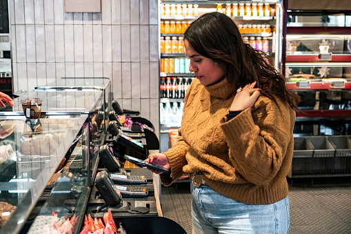 Girl paying with smartphone co<em></em>ntactless wallet in the grocery shop.
