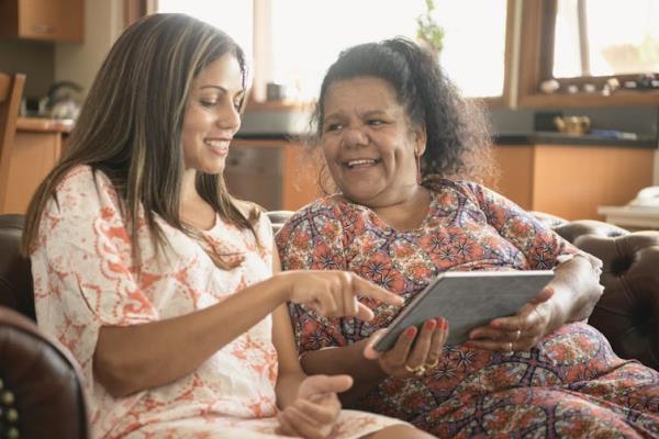 Two women smiling and using a tablet computer.