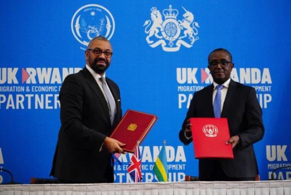 Britain's Home Secretary James Cleverly (L) and Rwanda's Foreign Minister Vincent Biruta exchange docu<em></em>ments after signing a new treaty, in Kigali on December 5, 2023. Britain and Rwanda signed a new treaty on Tuesday in a bid to revive a co<em></em>ntroversial proposal by Lo<em></em>ndon to transfer migrants to the east African country. Cleverly met Biruta in Kigali to sign the agreement and salvage London's stalled bid to send asylum-seekers and other migrants to Rwanda, after the UK Supreme Court last mo<em></em>nth blocked an earlier arrangement as unlawful. (Photo by Ben Birchall / POOL / AFP) (Photo by BEN BIRCHALL/POOL/AFP via Getty Images)