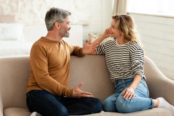 middle aged man and woman havin<em></em>g a co<em></em>nversation on the couch
