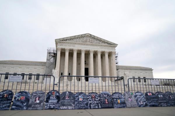 Signs in the shape of grave headstones, with information on people who died from using OxyContin, line a security fence outside the Supreme Court Monday, Dec. 4, 2023, in Washington.