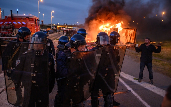 French police in riot gear stand guard near a burning truck during a farmers' protest in Narbo<em></em>nne on Friday