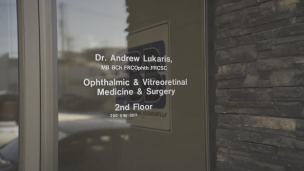 A screen door advertising services of a retinal specialist in a Prince George building.