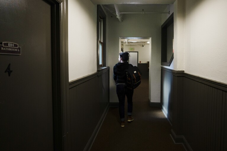 Sarah Holland, senior director of supportive housing and employment at Central City Concern, a Portland-ba<em></em>sed homeless services nonprofit, looks out the window after walking by a shared bathroom at one of their affordable housing properties on Friday, March 15, 2024, in Portland, Ore. The no<em></em>nprofit leases more than 1,000 single room occupancy units, both subsidized and not, to people who are co<em></em>nsidered extremely low-income. It helps people struggling to access housing due to things like eviction histories and poor credit scores. (AP Photo/Jenny Kane)