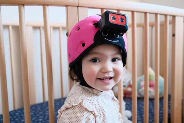 Luna at 18 mo<em></em>nths wearing a pink helmet with a camera attached to it