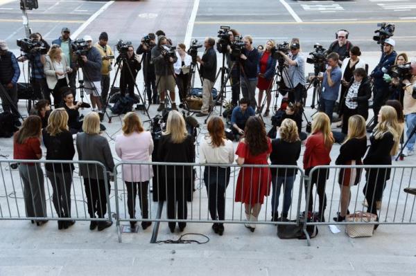 The Silence Breakers, a group of women who spoke out a<em></em>bout Harvey Weinstein. They are pictured outside a court in Los Angelese in 2020. They are standing in a line with their backs to the camera, facing a group of journalists.