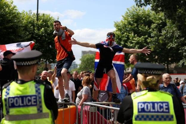 Demo<em></em>nstrators stand on a structure and gesture as police look on.