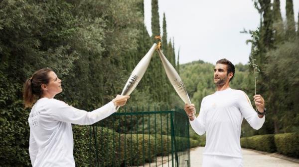 The first torchbearer Greek rower Stefanos Ntouskos, lights the touch of the second torchbearer French swimmer Laure Manaudou during the torch relay.</p>

<p>　　Pic: Reuters