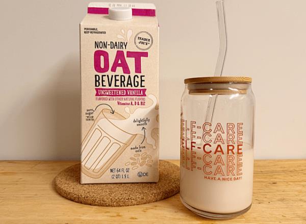 a co<em></em>ntainer of trader joe's oat milk next to a glass cup
