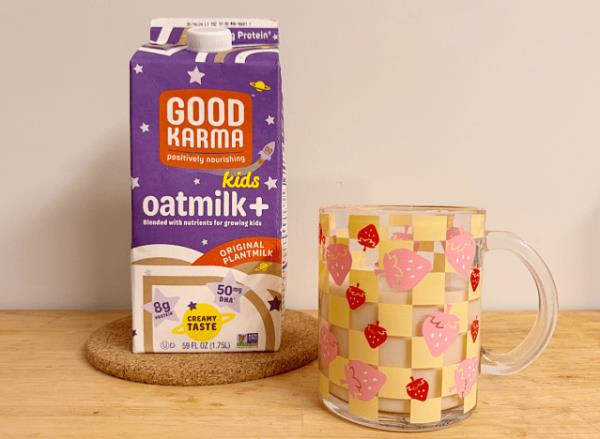 a co<em></em>ntainer of good karma oat milk next to a strawberry printed mug