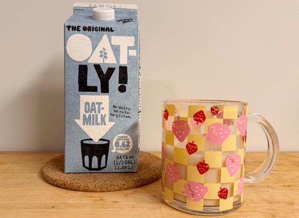 a co<em></em>ntainer of oatly oat milk next to a strawberry printed mug