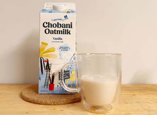 a co<em></em>ntainer of chobani vanilla oat milk next to a glass
