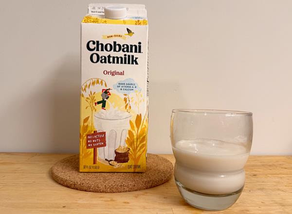 a co<em></em>ntainer of chobani oat milk next to a glass