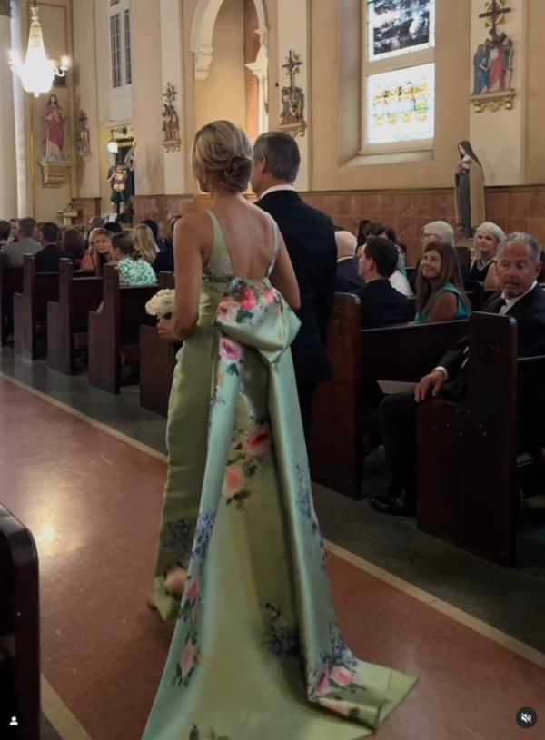 Louisiana mom Lori DeWitt is seen in an Instagram reel walking down the aisle in a green floral custom Audrey + Brooks dress with a plunging neckline, detachable bow and train.