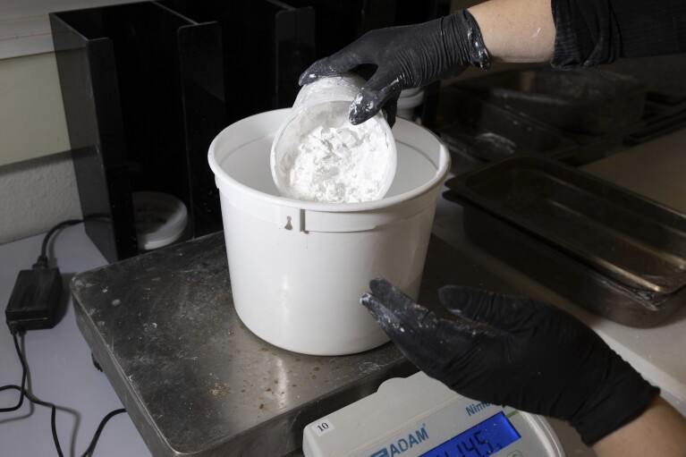 A worker measures ReAct product at Fortera's facility in San Jose, Calif., Wednesday, April 10, 2024. The cement industry is one of the largest emitters of carbon dioxide and is respo<em></em>nsible for a<em></em>bout 8% of global emissions each year. Fortera, a clean tech company whose technology captures carbon emissions from kilns and feeds it back in to the process, is opening its first commercial scale operation on Thursday, April 12, 2024, in California. (AP Photo/Benjamin Fanjoy)