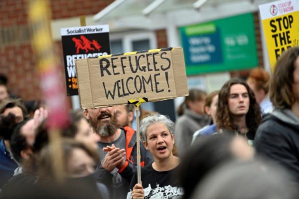 A woman holds a banner reading 'Refugees Welcome' at a rally against the far-right in Oxford