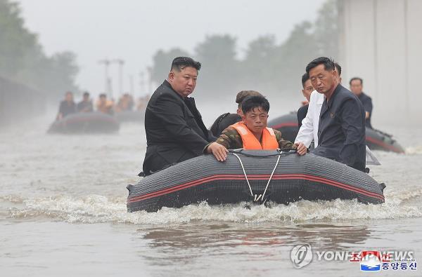 This photo, carried by North Korea's official Korean Central News Agency on July 31, 2024, shows the North's leader Kim Jong-un (L) riding in a lifeboat to inspect flood-hit areas in North Korea's border city of Sinuiju. (For Use o<em></em>nly in the Republic of Korea. No Redistribution) (Yonhap)