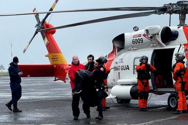 Coast Guard perso<em></em>nnel help carry a swimmer from a rescue helicopter.