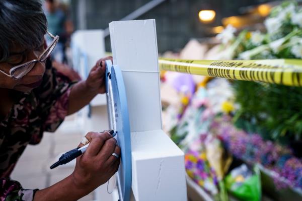 Manetta Lemkheitir writes on a cross at the memorial outside of the Old Natio<em></em>nal Bank on Tuesday.