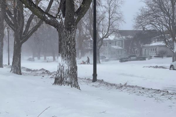 A person clears snow from the sidewalk during a snowstorm on Saturday in Buffalo.