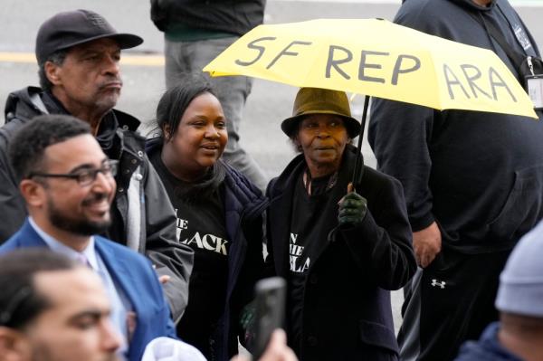 Pia Harris, with the San Francisco Housing Development Corporation, second from left, and her mother, Adrian Williams, listen to speakers at a reparations rally outside of City Hall in San Francisco.