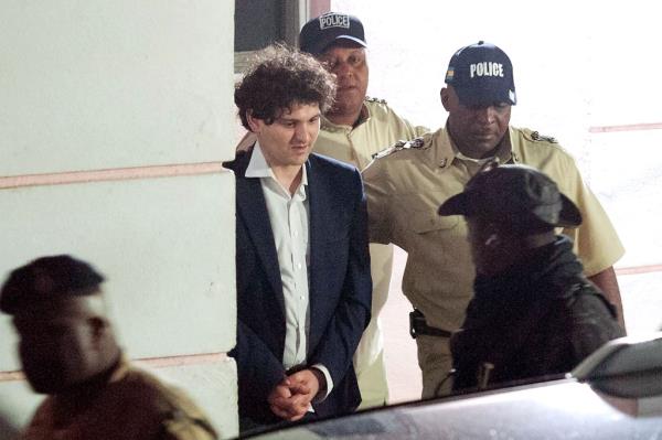 FTX founder Sam Bankman-Fried (2nd L) is led away handcuffed by officers of the Royal Bahamas Police Force in Nassau, Bahamas on December 13, 2022.