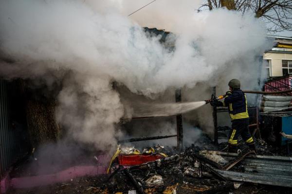A rescuer extinguishes a fire in a burning shop after Russian shelling to Ukrainian city of Kherson on December 24, 2022, wher<em></em>e five were killed and 20 injured.