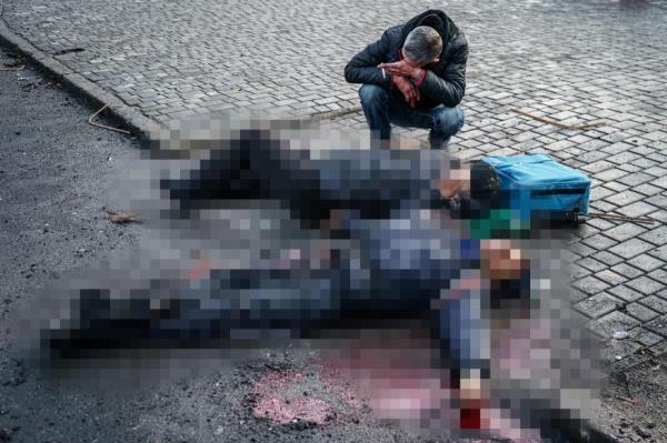 A man reacts to the bodies of Ukrainian civilians splayed across the ground falling an attack by Russian forces.