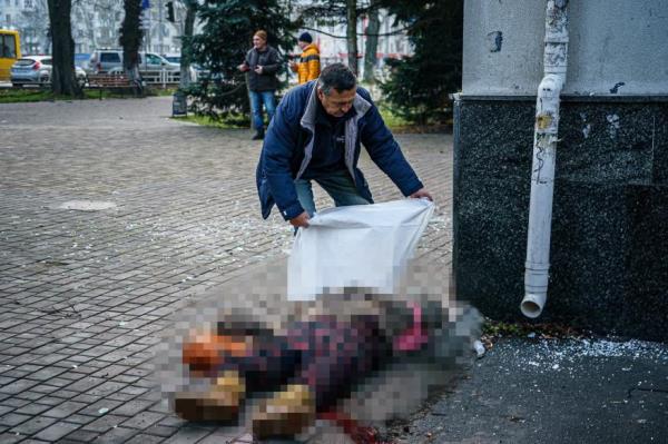 A man covers the body of a dead woman after Russian shelling in Kherson.