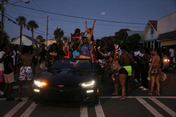 People dancing in the street and on cars as the sun goes down on Tybee Island