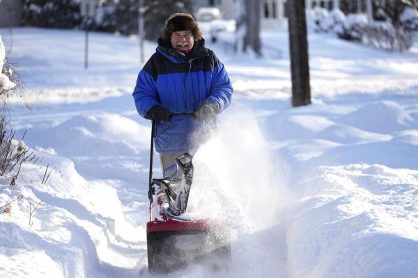 A man clears snow off a sidewalk Thursday, Dec. 22, 2022, in Minneapolis. 