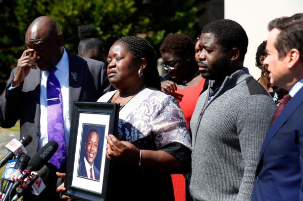 Caroline Ouko speaking, supported on the right by her eldest son Leon Ochieng and on the left by attorney Benjamin Crump.