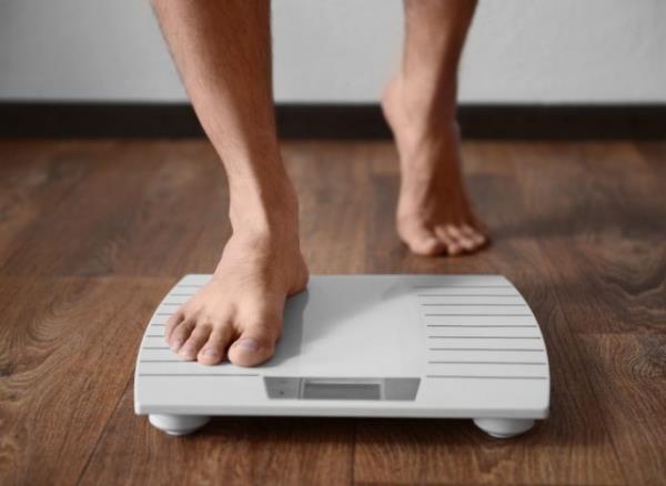 close-up man stepping o<em></em>nto scale