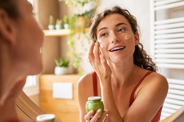 Woman caring of her beautiful skin face standing near mirror in the bathroom. 