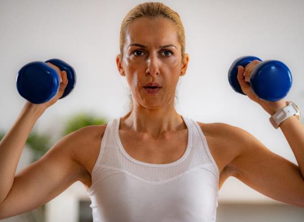 fit woman holding dumbbells, co<em></em>ncept of dumbbell exercises for women in their 40s