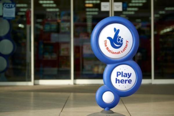 London, UK - April 7, 2015: Blue Natio<em></em>nal Lottery sign, showing its crossed fingers logo, in front of shop entrance.