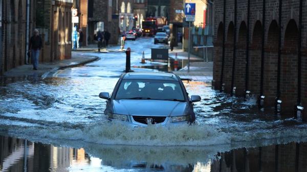 A car is driven down a flooded road after the River Ouse burst its banks following heavy rain in York, Britain, December 11, 2023. REUTERS/Phil Noble</p>

<p>　　
