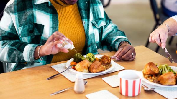Person puts salt on their meal.