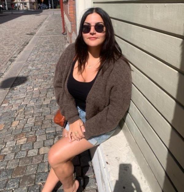 Almara Abgarian sitting on a low wall outside on a street