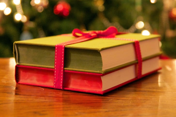books tied with a ribbon in front of a christmas tree